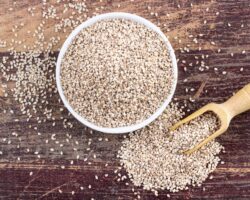Sesam in einer Schüssel, in einem Holzlöffel und auf dem Tisch verstreut