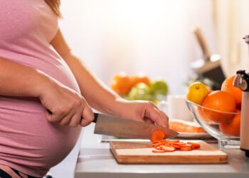 Eine schwangere Frau schneidet Karotten in Scheiben