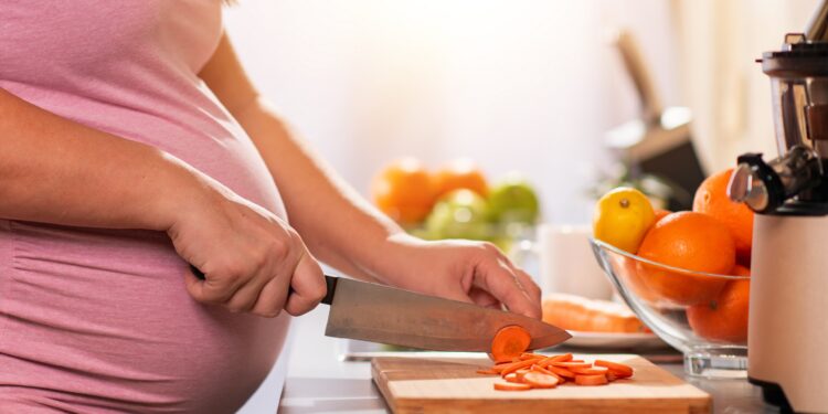 Eine schwangere Frau schneidet Karotten in Scheiben