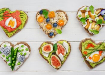 Brotscheiben in Herzform, die mit gesunden Lebensmitteln belegt sind.