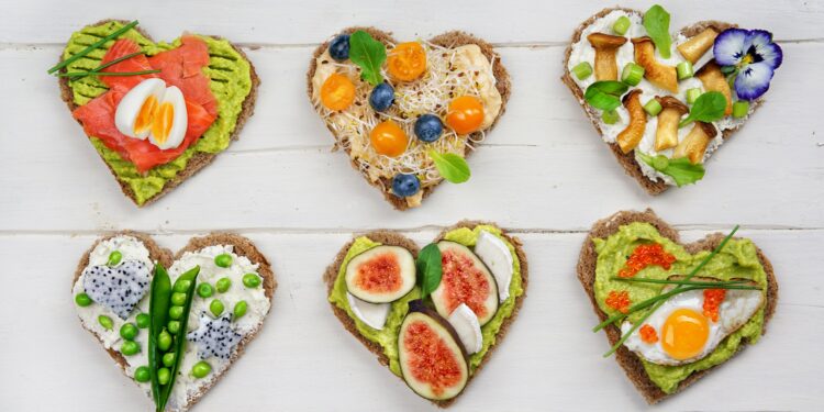 Brotscheiben in Herzform, die mit gesunden Lebensmitteln belegt sind.