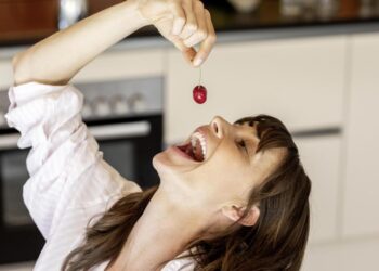 Eine Frau isst genussvoll eine Kirsche.