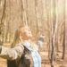 Frau genießt Sonnenstrahlen bei einer Wanderung im herbstlichen Wald