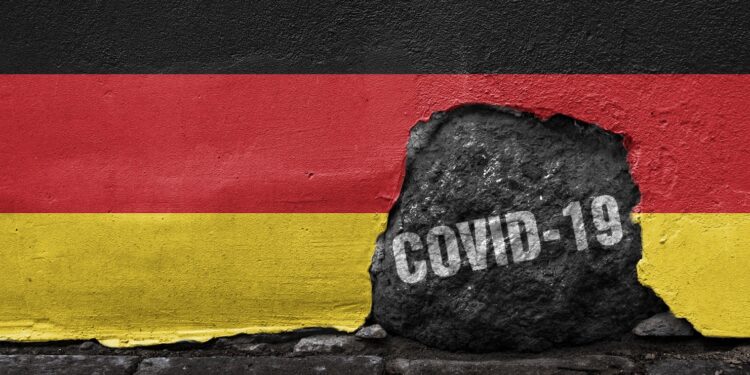 Eine Deutschlandfahne mit einem Loch in dem "COVID-19" steht.