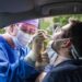 Ärztin macht bei einem im Auto sitzenden Mann einen Nasenabstrich