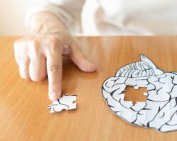 Seniorin mit einem Gehirn-Puzzle bei dem das letzte Puzzlestück noch fehlt.