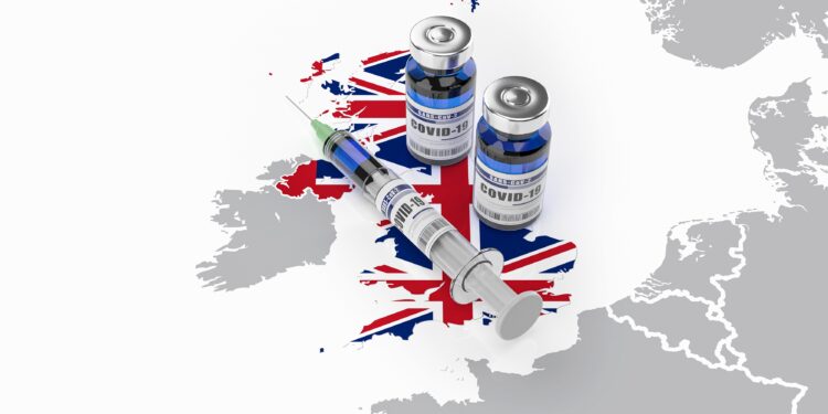 Auf einer Karte von Großbritannien liegt eine Spritze und zwei Dosen eines COVID-19-Impfstoffes.