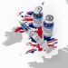 Auf einer Karte von Großbritannien liegt eine Spritze und zwei Dosen eines COVID-19-Impfstoffes.