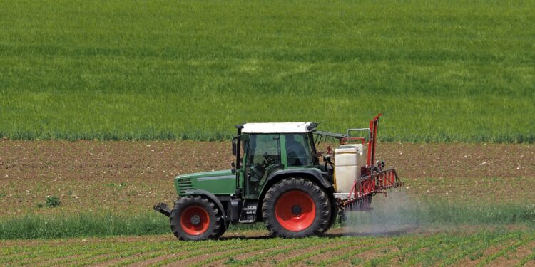 Traktor beim Versprühen von Pflanzenschutzmitteln auf einem Acker