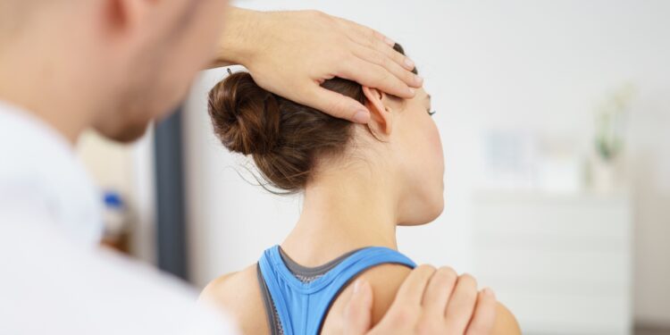 Physiotherapeut untesucht den Nacken einer Patientin.