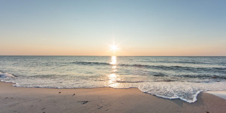 Strand am Meer mit Sonne am Horizont