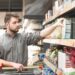 Ein Mann nimmt eine Packung Müsli aus einem Regal im Supermarkt.