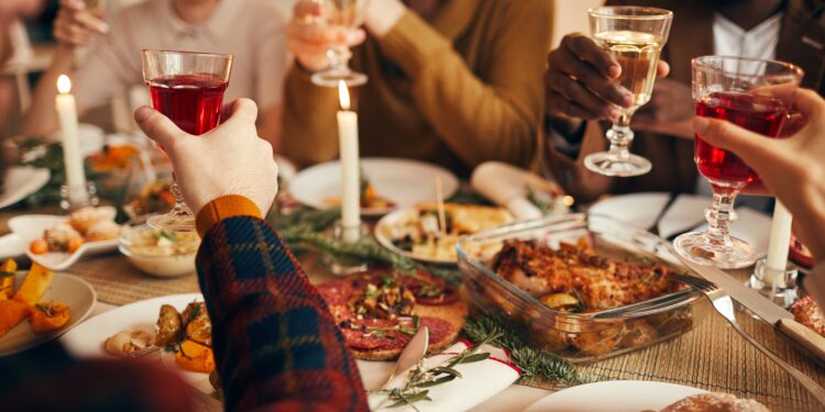 Freunde stoßen mit einem Glas Wein beim Weihnachtsessen an.