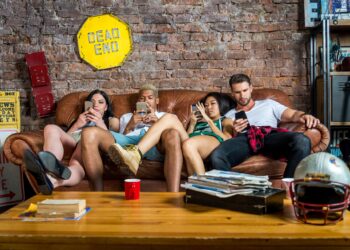 Vier Jungendliche sitzen auf einem Sofa und schauen auf ihre Smartphones.