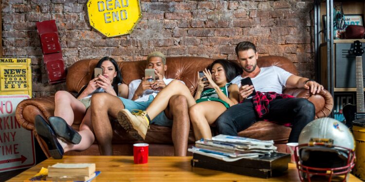 Vier Jungendliche sitzen auf einem Sofa und schauen auf ihre Smartphones.