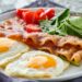 Low Carb Frühstück mit Eiern, Speck, Tomaten und Salat auf einem Teller