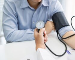 Arzt misst bei einem Patienten den Blutdruck