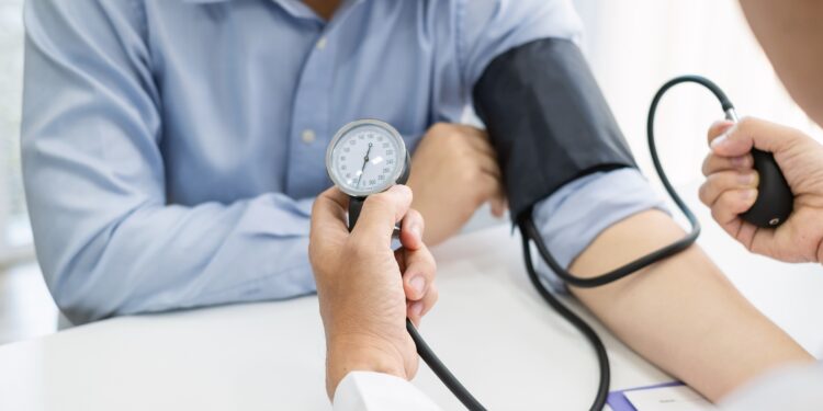 Arzt misst bei einem Patienten den Blutdruck