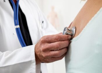 Ein Arzt überprüft die Lungenfunktion und den Herzschlag einer Patientin.