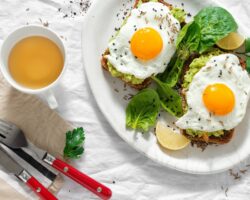 Gebratene Eier auf Brotscheiben mit Avocado neben einer Tasse Tee