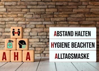 Aufeinander gestapelte Würfel und ein Leuchtkasten, die die AHA-Regeln aufzeigen: Abstand halten, Hygiene beachten, Alltagsmaske