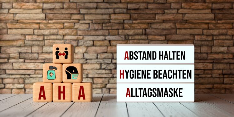 Aufeinander gestapelte Würfel und ein Leuchtkasten, die die AHA-Regeln aufzeigen: Abstand halten, Hygiene beachten, Alltagsmaske