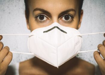 Junge Frau legt eine FFP2-Maske an