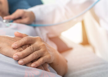 Ältere Frau wird im Krankenhausbett von einem Arzt untersucht