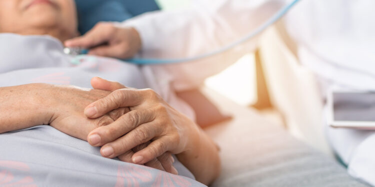 Ältere Frau wird im Krankenhausbett von einem Arzt untersucht