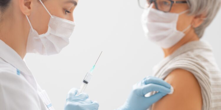 Ärztin verabreicht einer Seniorin eine Impfung