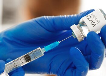 Hände in blauen Handschuhen bereiten Covid-19-Impfstoff für die Impfung vor