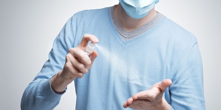 Ein Mann sprüht sich ein Desinfektionsmittel auf die Hand.