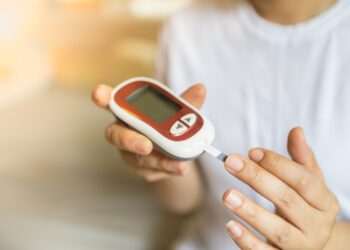 Frau misst mit einem Glukosemessgerät am Finger ihren Blutzuckerspiegel