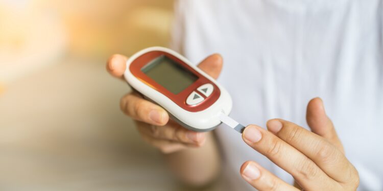 Frau misst mit einem Glukosemessgerät am Finger ihren Blutzuckerspiegel