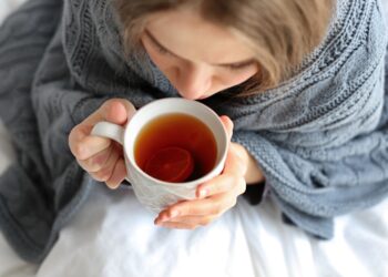 Junge Frau mit einer Tasse Tee im Bett