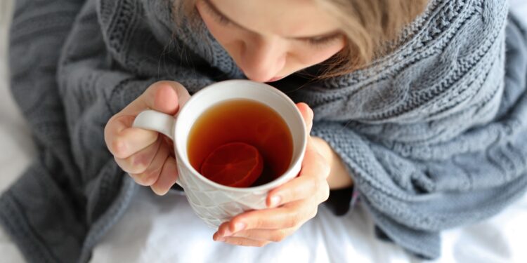 Junge Frau mit einer Tasse Tee im Bett
