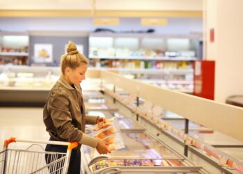 Eine Frau nimmt einen Fisch aus einer Tiefkühltruhe im Supermarkt.