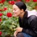 Junge Frau riecht im Garten an Rosen