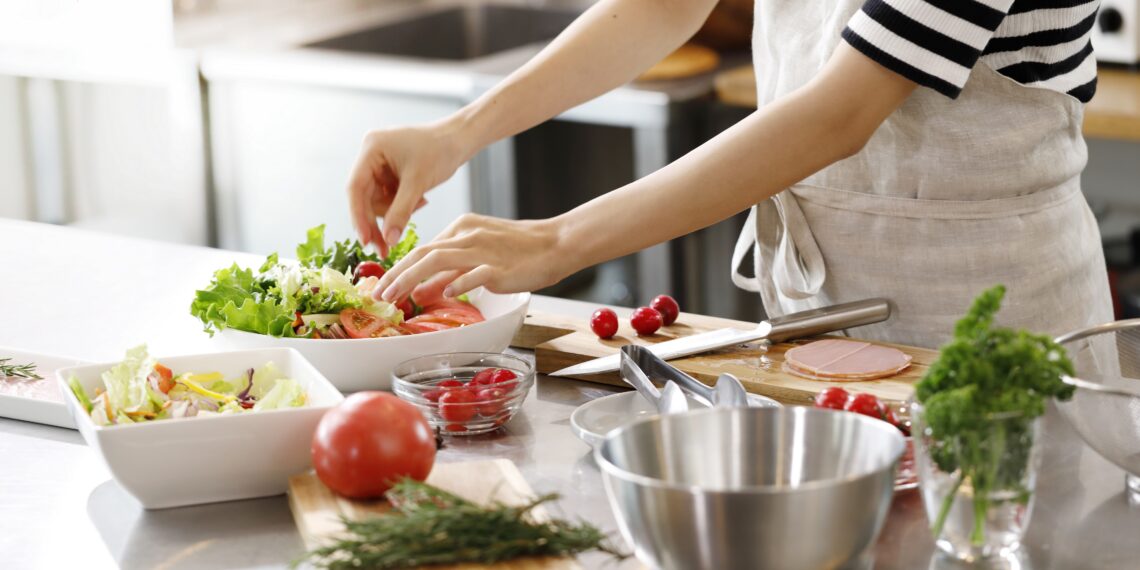 Frau bereitet einen gemischten Salat in einer Küche zu