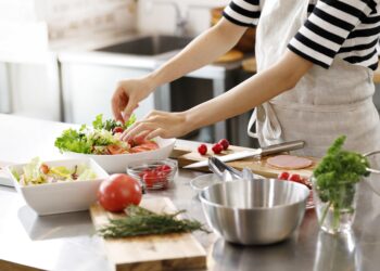 Frau bereitet einen gemischten Salat in einer Küche zu