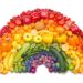 Verschiedenfarbige Obst und Gemüsesorten sind in Form eines Regenbogens angeordnet.