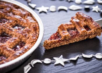 Ein Stück Linzertorte auf einer dunklen Oberfläche.