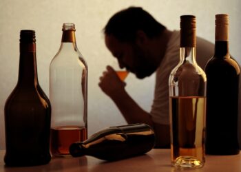 Mann mit verschiedenen Flaschen Alkohol.