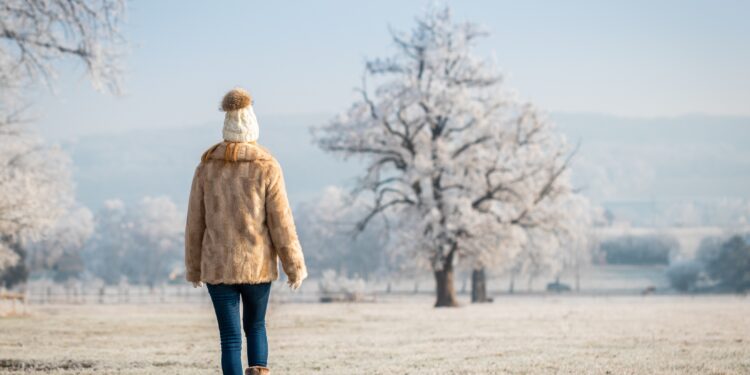 Frau macht einen Spaziergang in winterlicher Landschaft