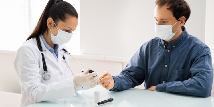 Ärztin mit Maske checkt Blutzucker von einem Patienten mit Maske