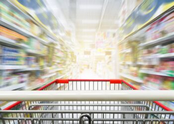 Supermarktgang mit leerem roten Einkaufswagen