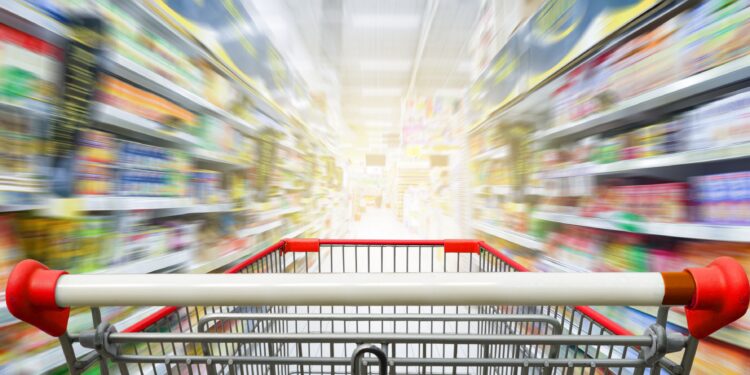 Supermarktgang mit leerem roten Einkaufswagen