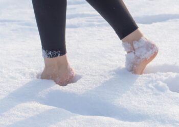 Frau stapft barfuß durch den Schnee