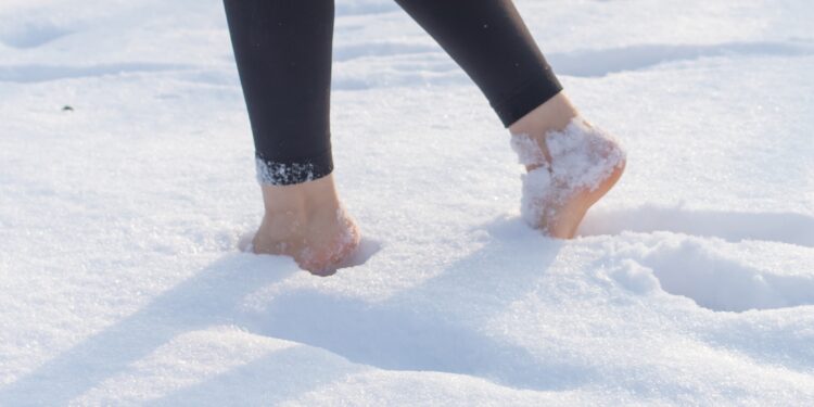 Frau stapft barfuß durch den Schnee