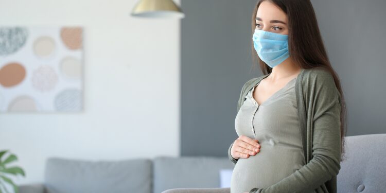 Schwangere Frau mit Gesichtsmaske.